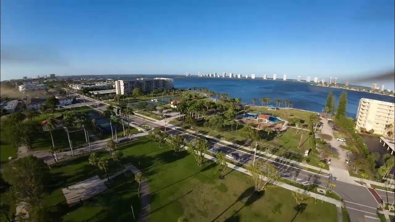 Aerial view of a coastal city with green parks, roads, buildings, and water.