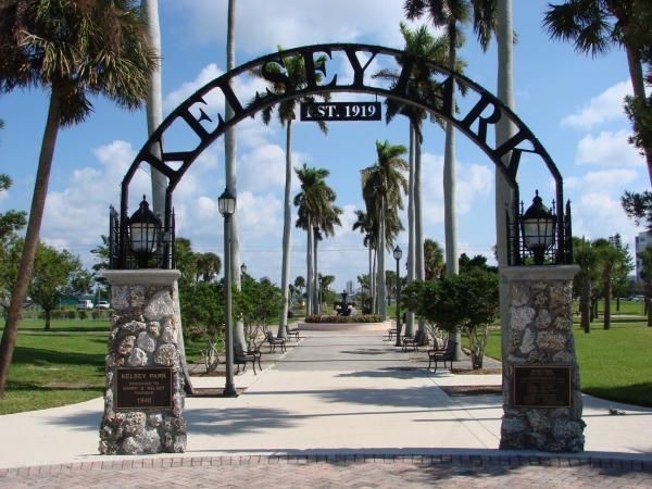 Entrance to Kelsey Park with archway and palm trees on a sunny day.